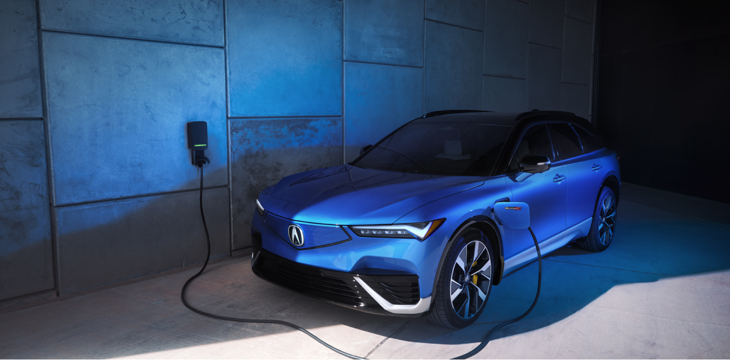 Side view of blue ZDX on white space, plugged into wall-mounted charger.