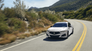 Front view of white TLX taking a turn on highway.