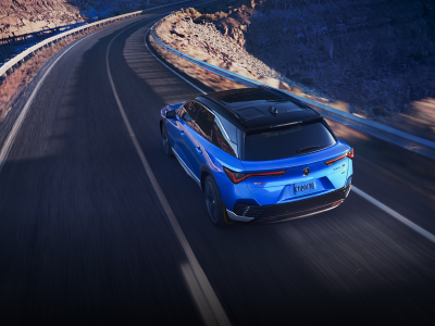 Bird’s eye 3/4 rear view of blue ZDX driving on desert highway at dusk.