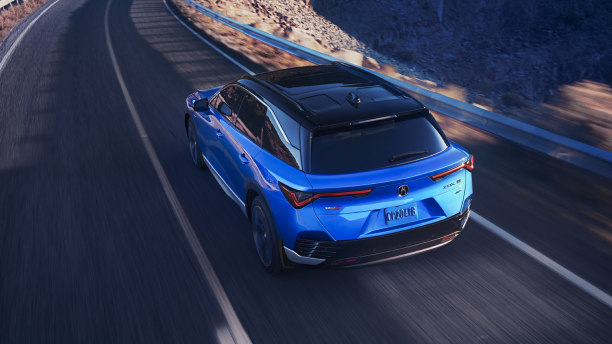 Bird’s eye 3/4 rear view of blue ZDX driving on desert highway at dusk.